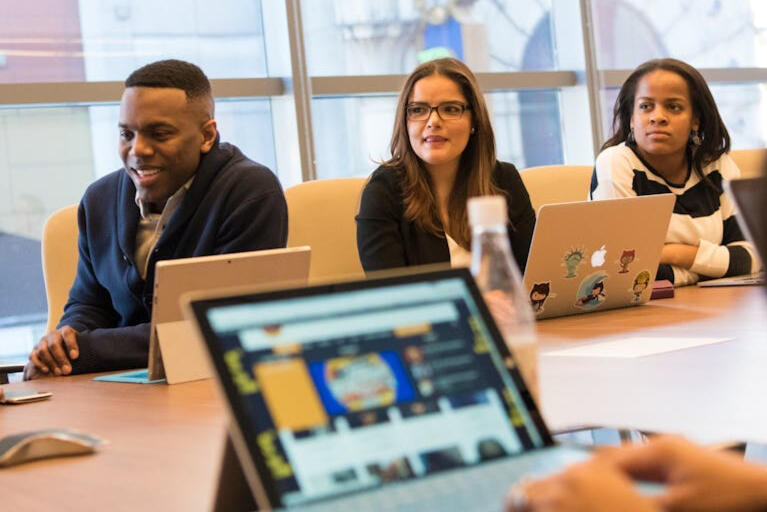 office workers at a tech firm reviewing information on laptops